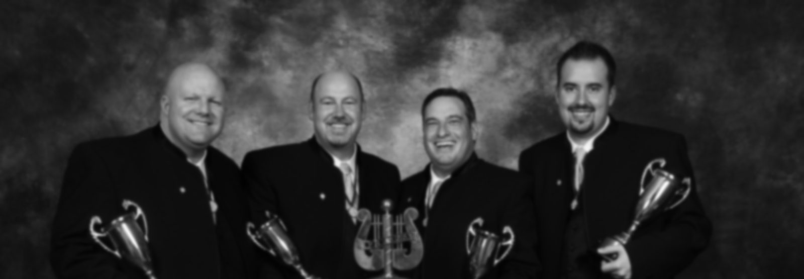 Crossroads, the 2009 International champions: four smiling men in black jackets holding trophies, in black and white.