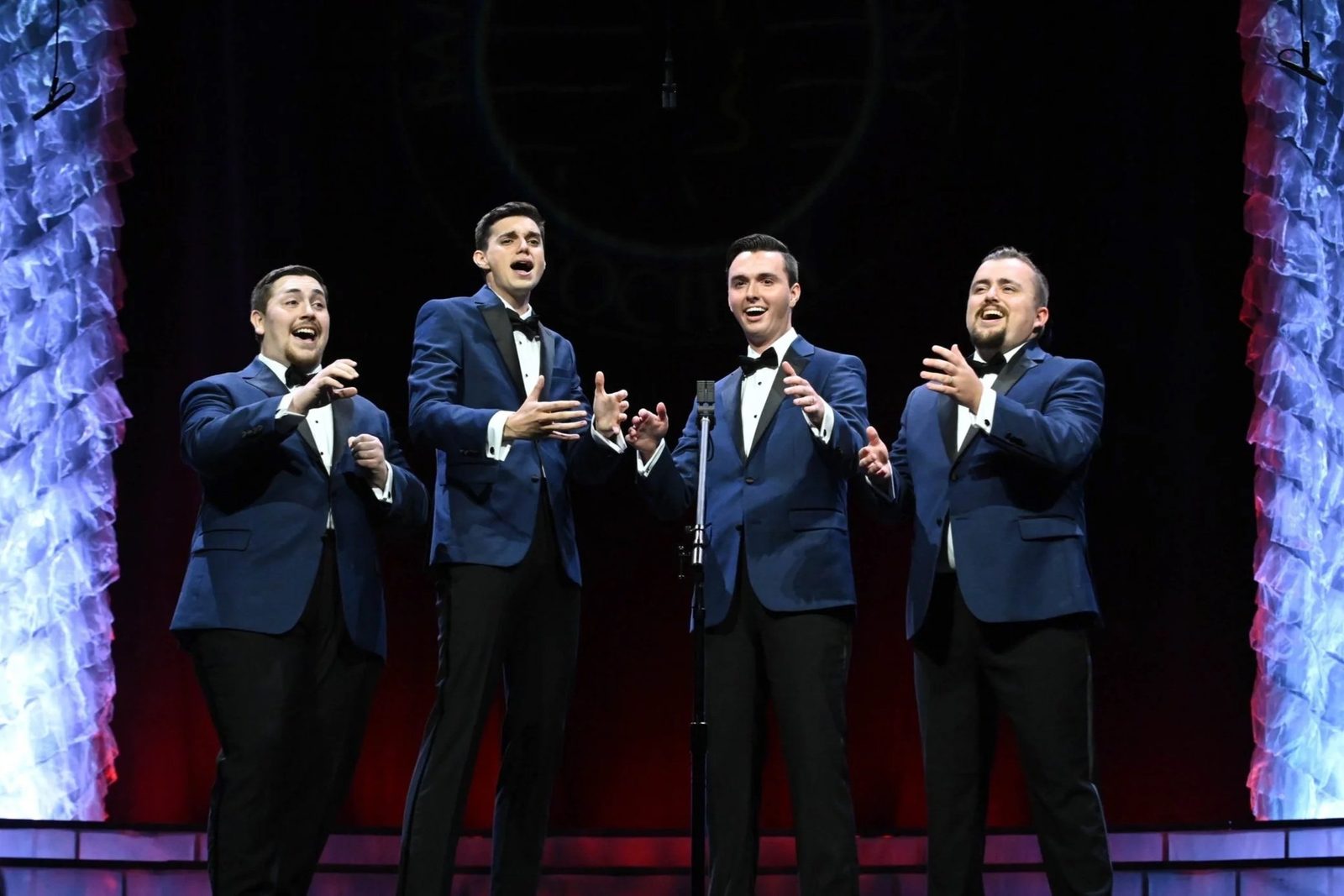 Full Effect, four men in blue tuxedo jackets and bow ties, singing around one microphone at the 2023 NextGen contest in Louisville.
