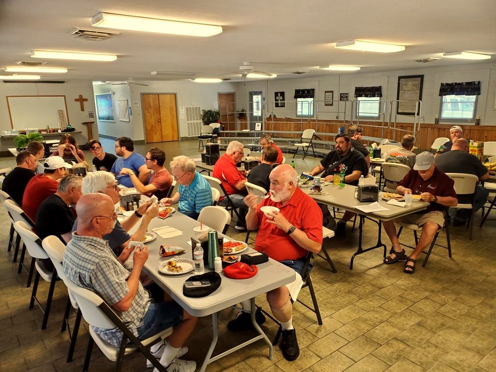 Chorus members sharing a meal at long tables in a retreat hall.
